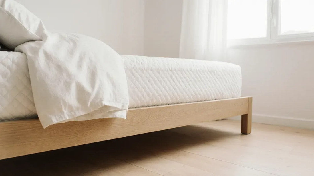 Side view of a low platform bed with a white mattress showing the bed's height above a wood floor